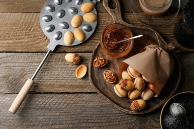 Photo of Freshly baked homemade walnut shaped cookies, boiled condensed milk, baking mold and cup of coffee on wooden table, flat lay