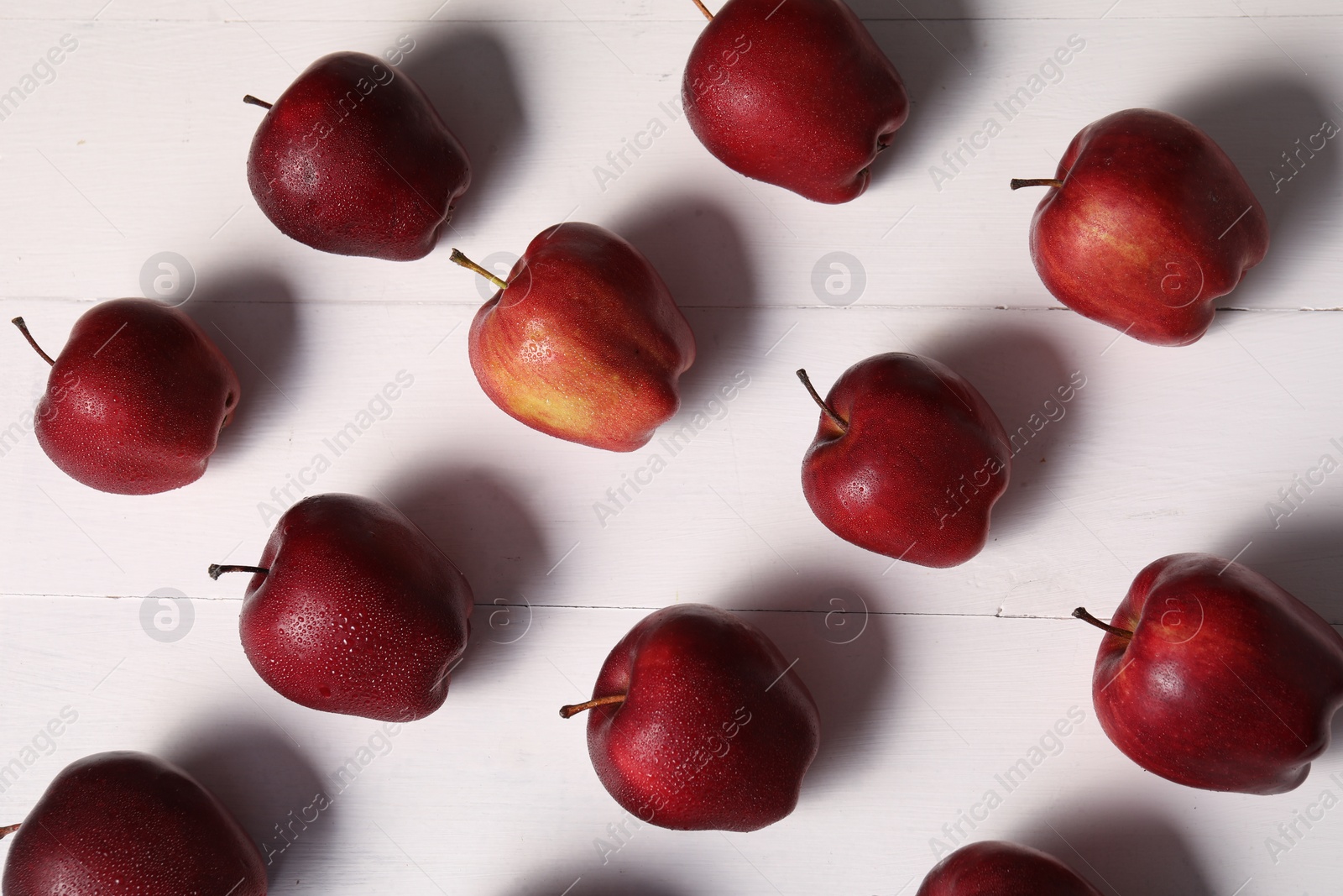 Photo of Fresh red apples with water drops on white wooden table, flat lay