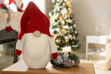 Photo of Cute Christmas gnome on wooden table in room with festive decorations. Space for text
