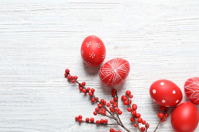 Photo of Flat lay composition with painted Easter eggs on wooden table, space for text