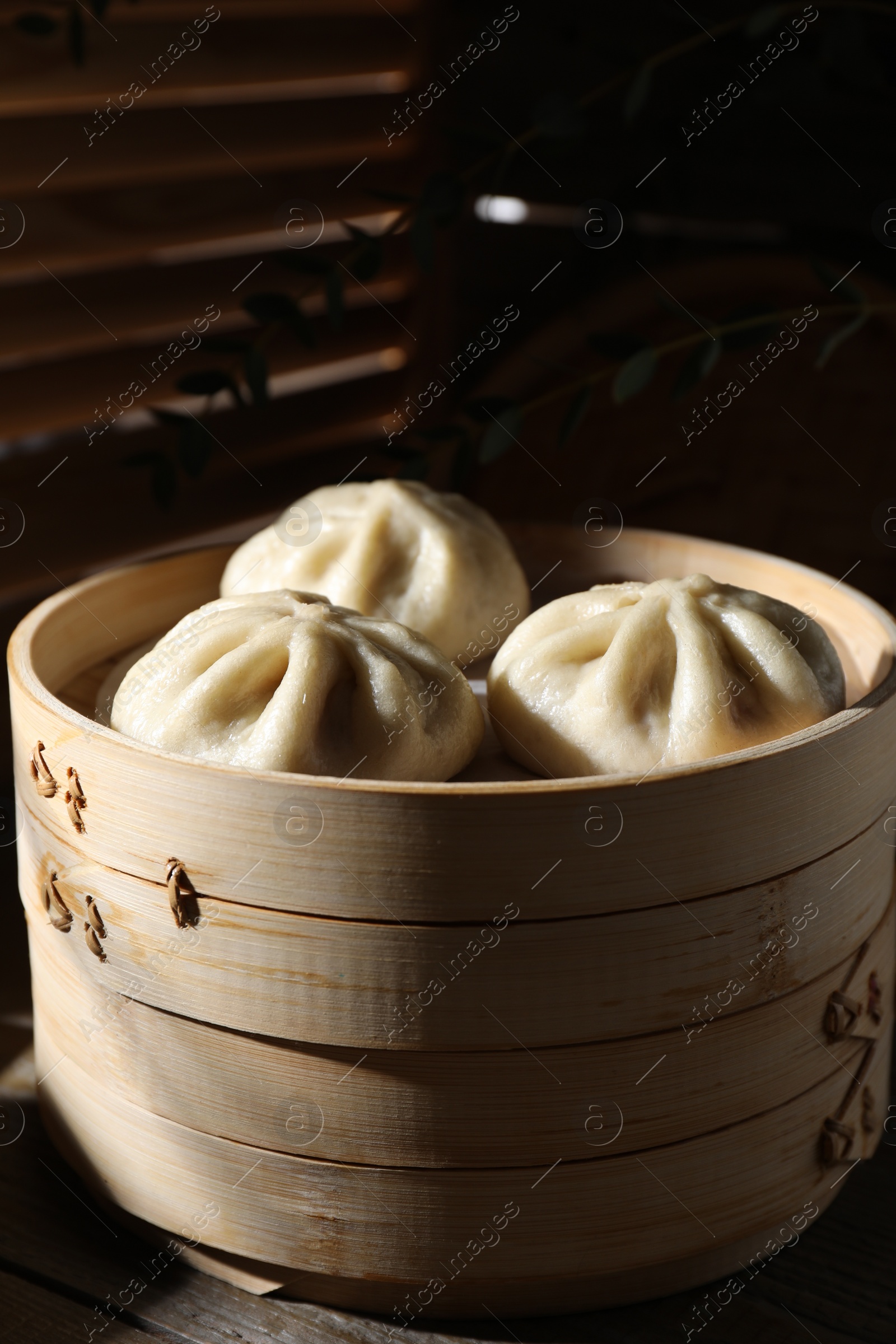 Photo of Delicious bao buns (baozi) on wooden table, closeup