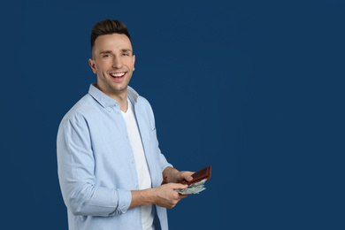 Photo of Emotional man with cash money and wallet on blue background. Space for text