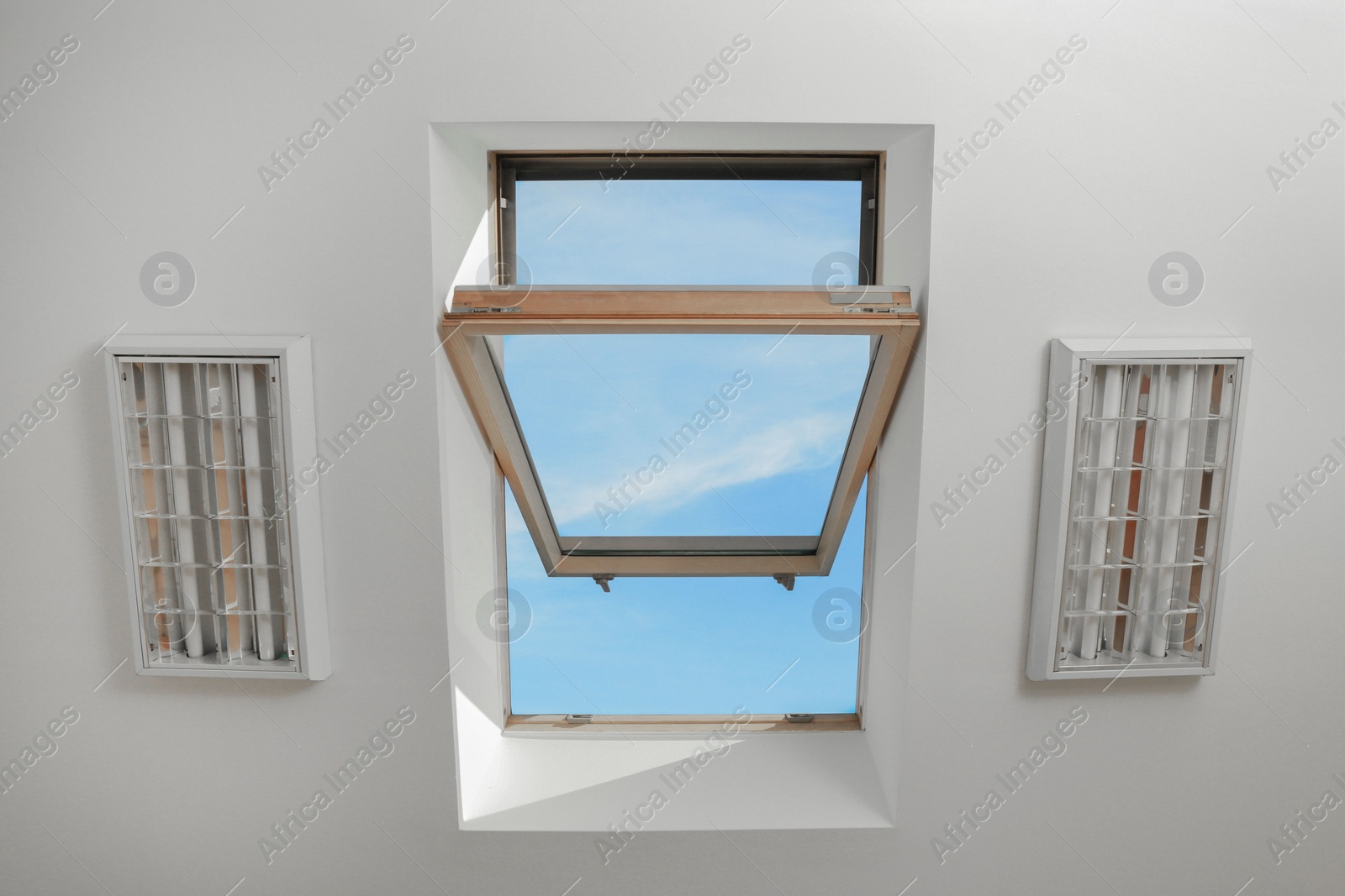 Photo of Open skylight roof window on slanted ceiling in attic room, bottom view