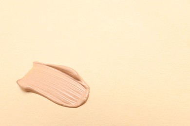 Smear of skin foundation on beige background. Space for text