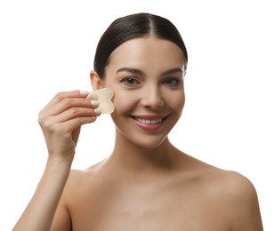 Beautiful young woman doing facial massage with gua sha tool on white background