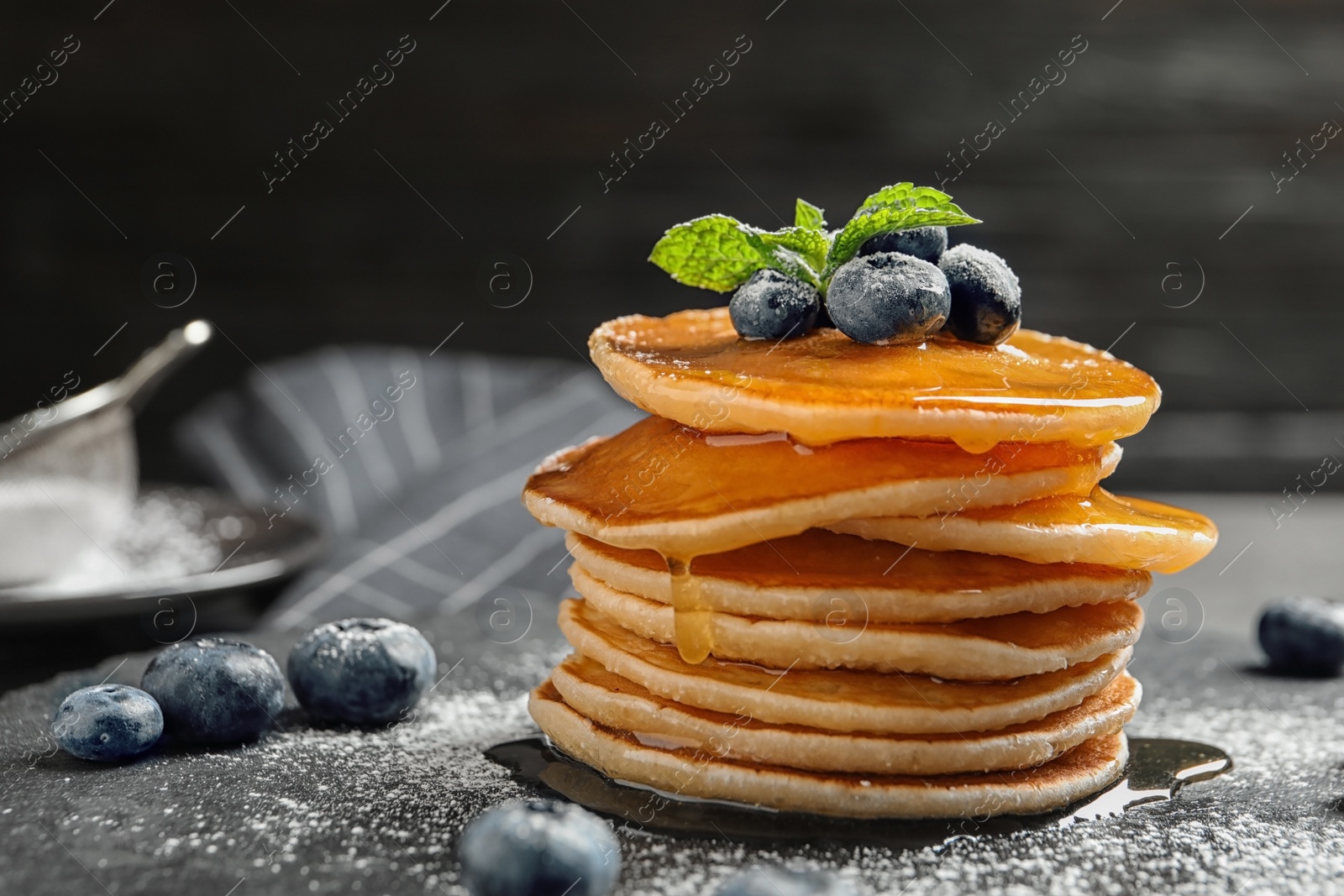 Photo of Tasty pancakes with berries and honey on slate plate