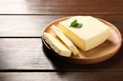 Photo of Cut tasty butter with parsley on wooden table