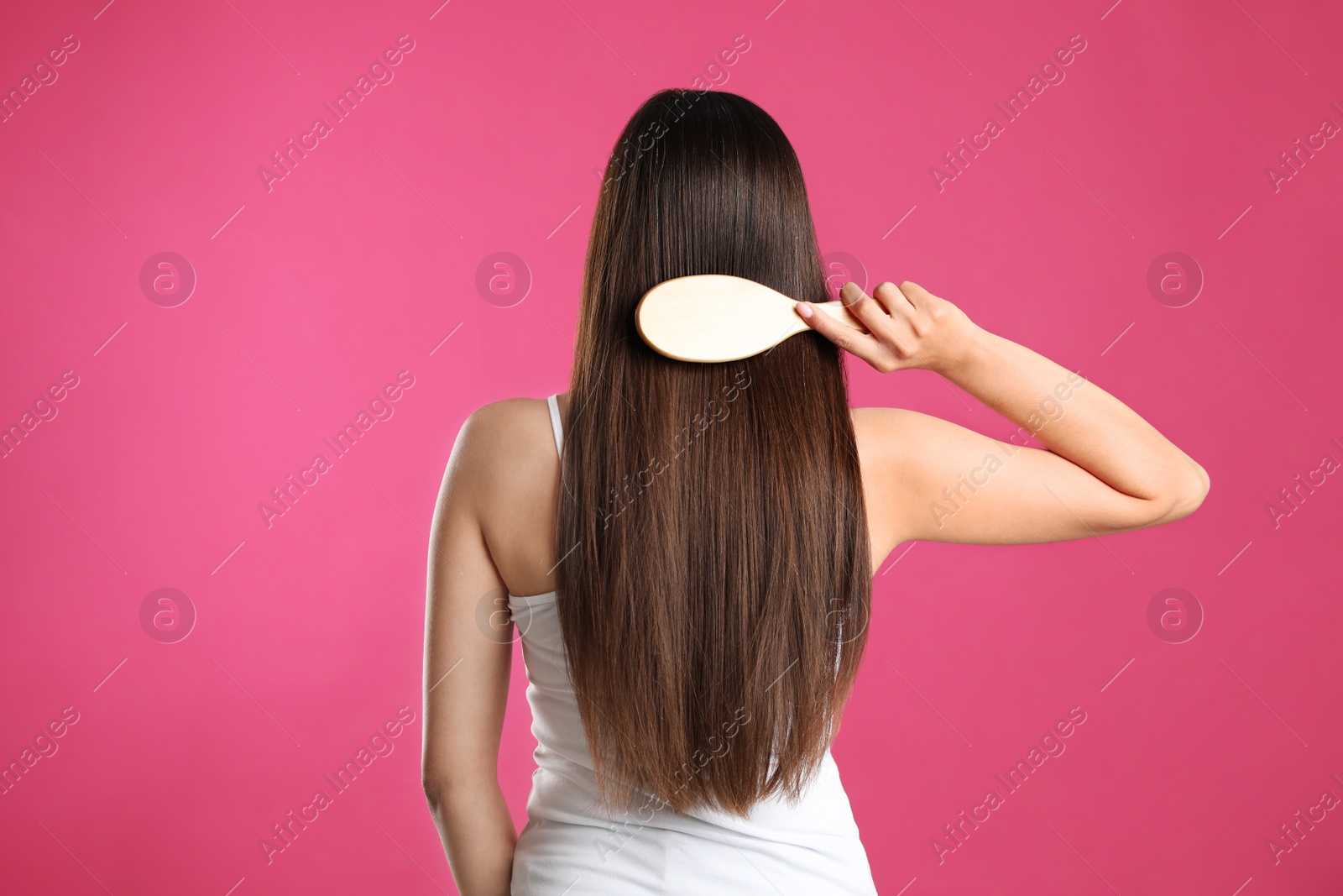 Photo of Back view of young woman with hair brush on color background