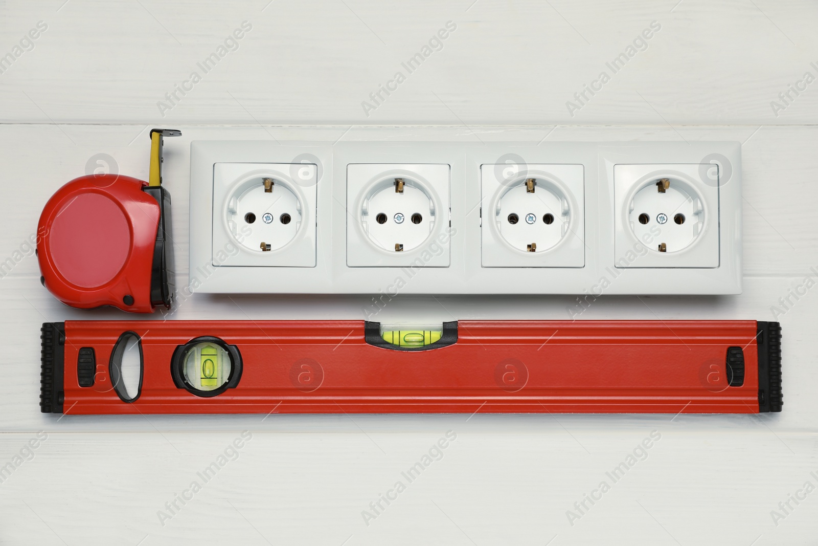 Photo of Power socket and set of electrician's tools on white wooden table, flat lay