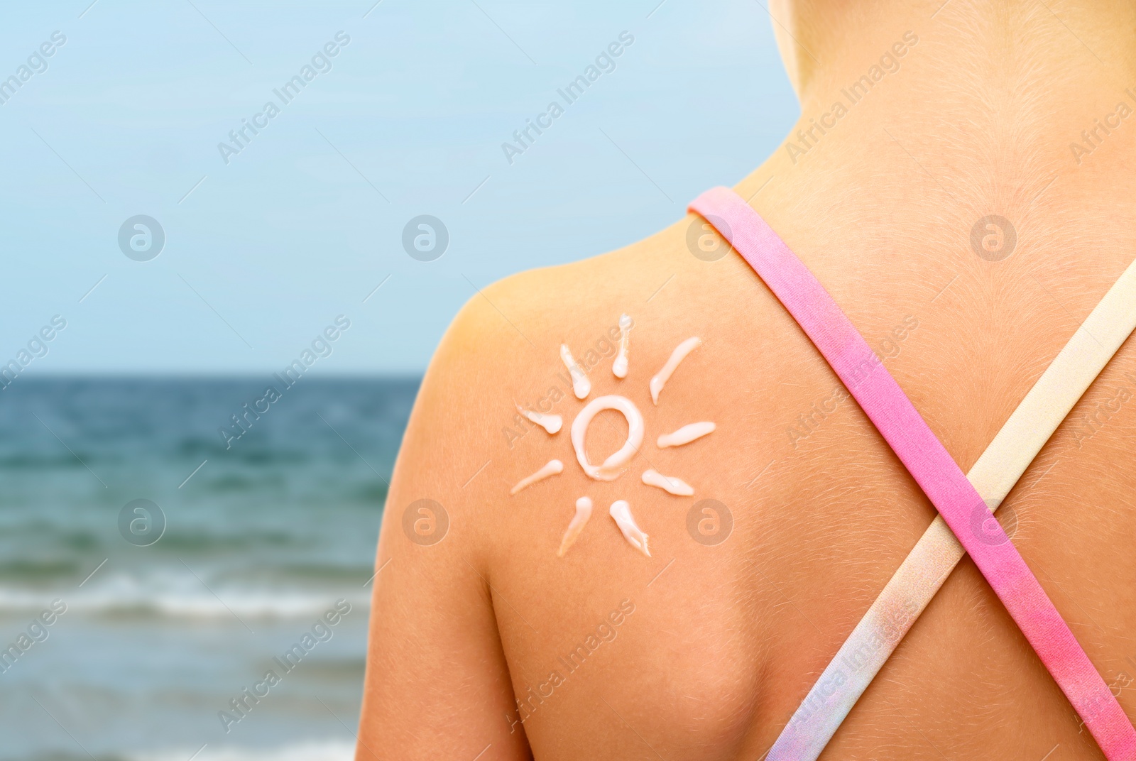 Image of Sun protection. Girl with sunblock on her back near sea, closeup