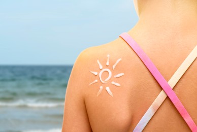 Image of Sun protection. Girl with sunblock on her back near sea, closeup