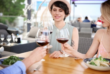 Photo of Group of friends with glasses of wine at table