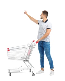 Young man with empty shopping cart on white background