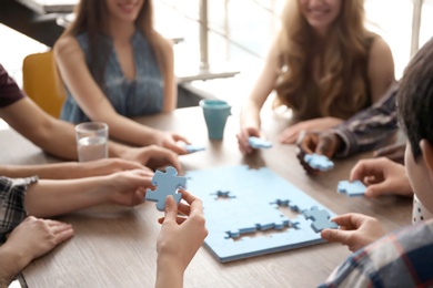 Photo of People with puzzle at table, closeup of hands. Unity concept