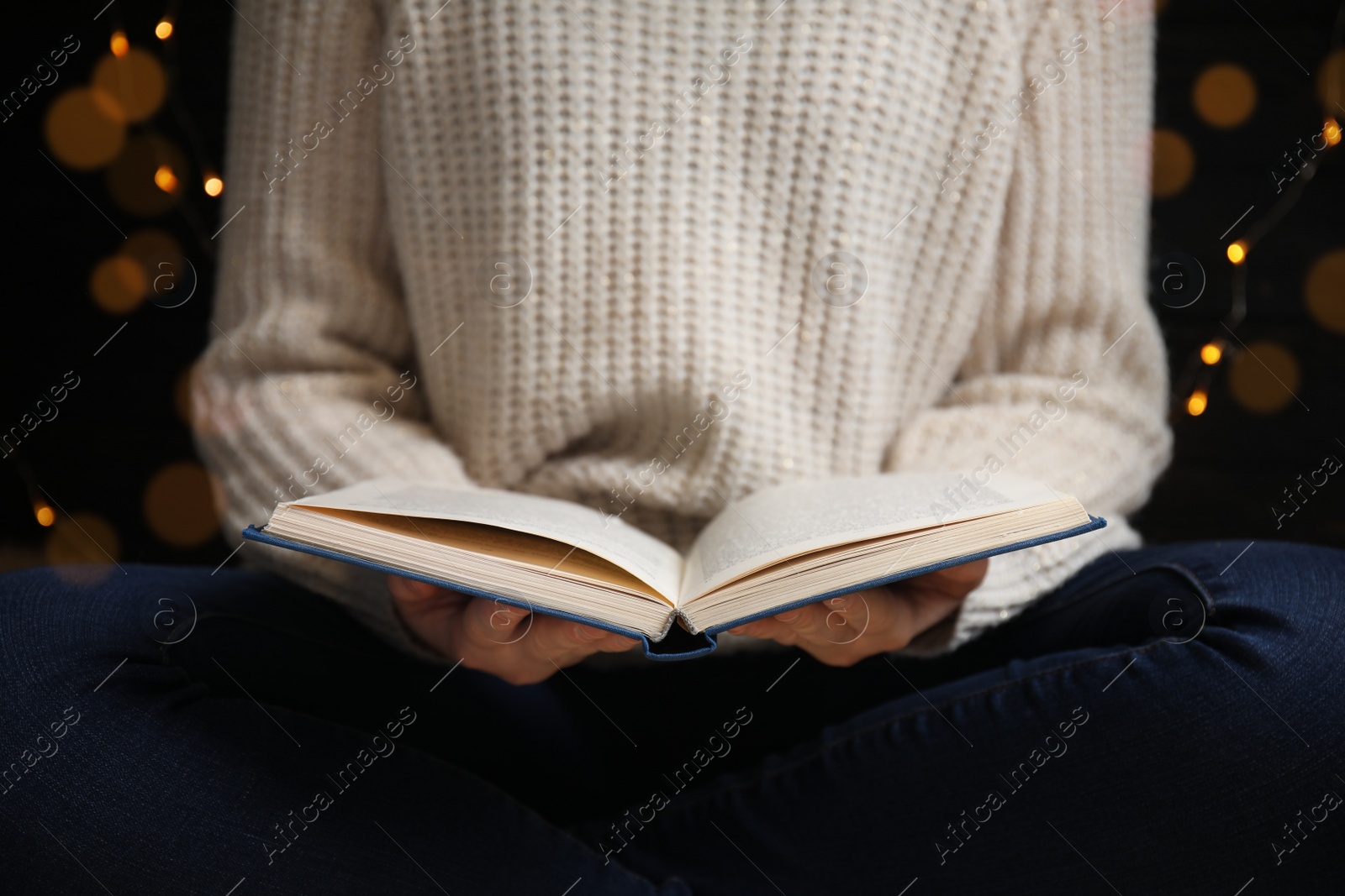 Photo of Young woman reading book at home, closeup