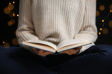 Photo of Young woman reading book at home, closeup