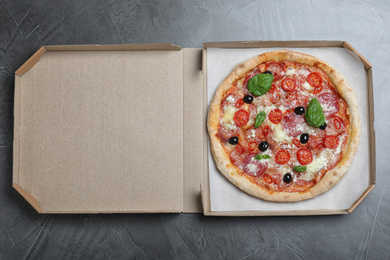 Photo of Delicious pizza Diablo in cardboard box on grey table, top view