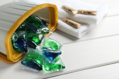 Container with laundry capsules on white wooden table