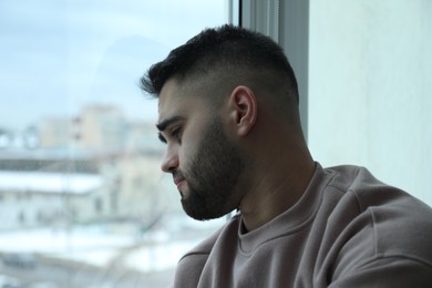 Photo of Portrait of sad man near window at home