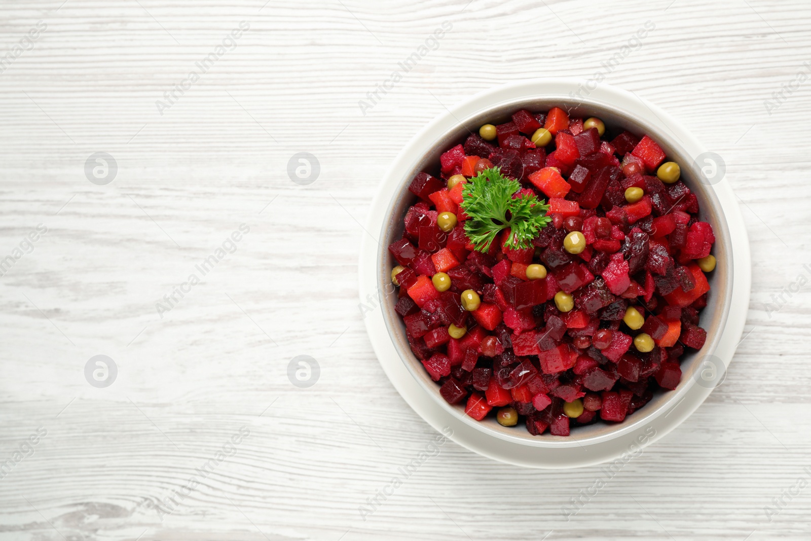 Photo of Traditional Russian salad vinaigrette on white wooden table, top view. Space for text