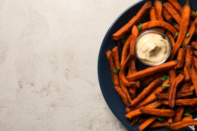 Photo of Delicious sweet potato fries served with sauce on light table, top view. Space for text