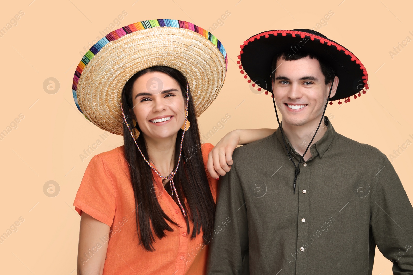 Photo of Lovely couple woman in Mexican sombrero hats on beige background