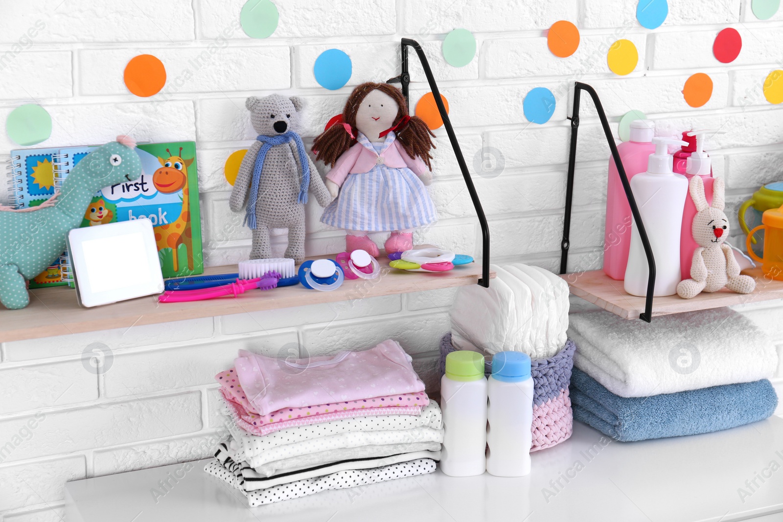 Photo of Baby accessories near white brick wall in nursery room