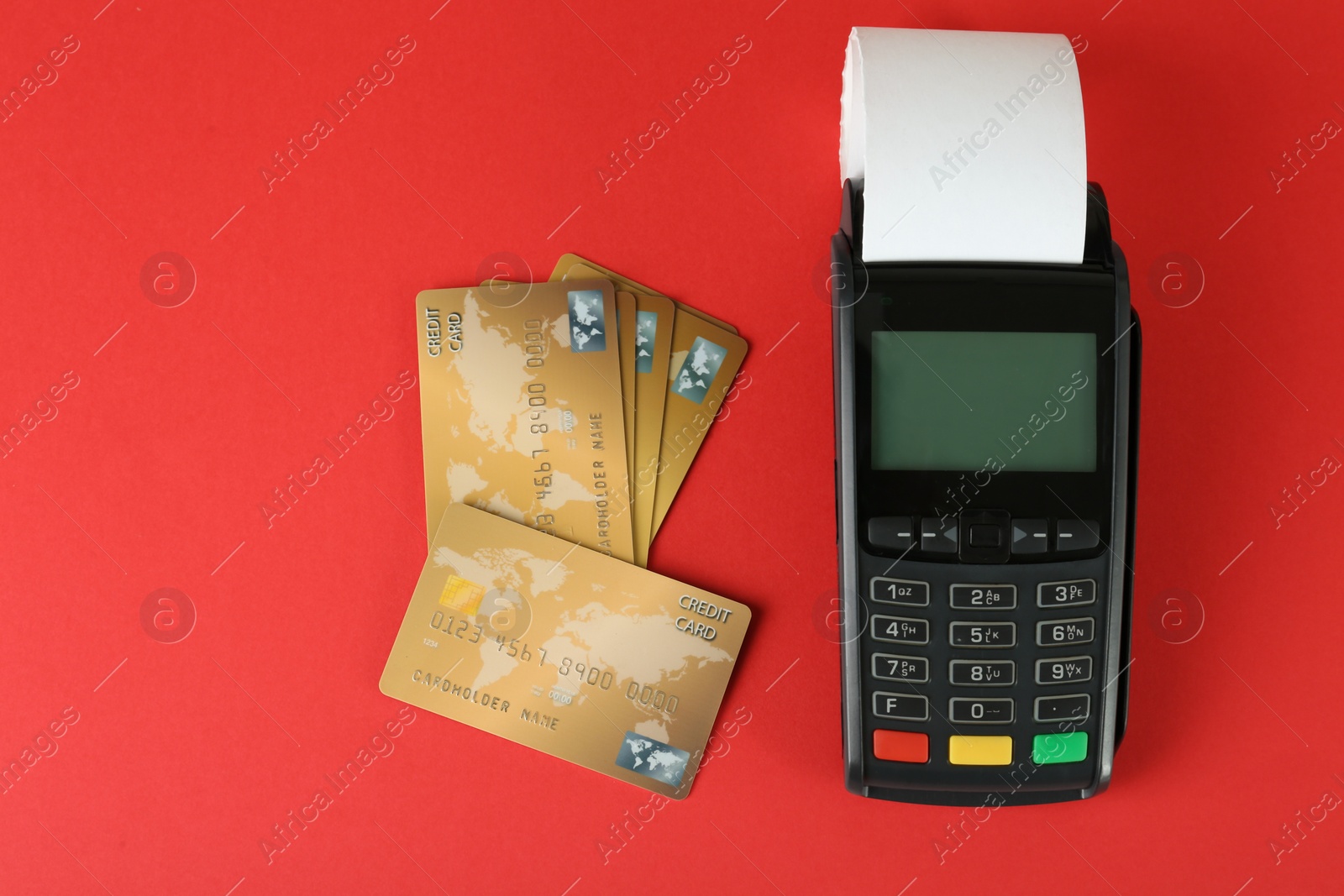 Photo of New modern payment terminal and credit cards on red background, flat lay