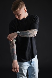 Photo of Young man with tattoos on black background
