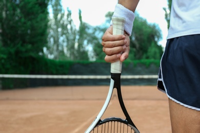 Sportsman with racket at tennis court, closeup