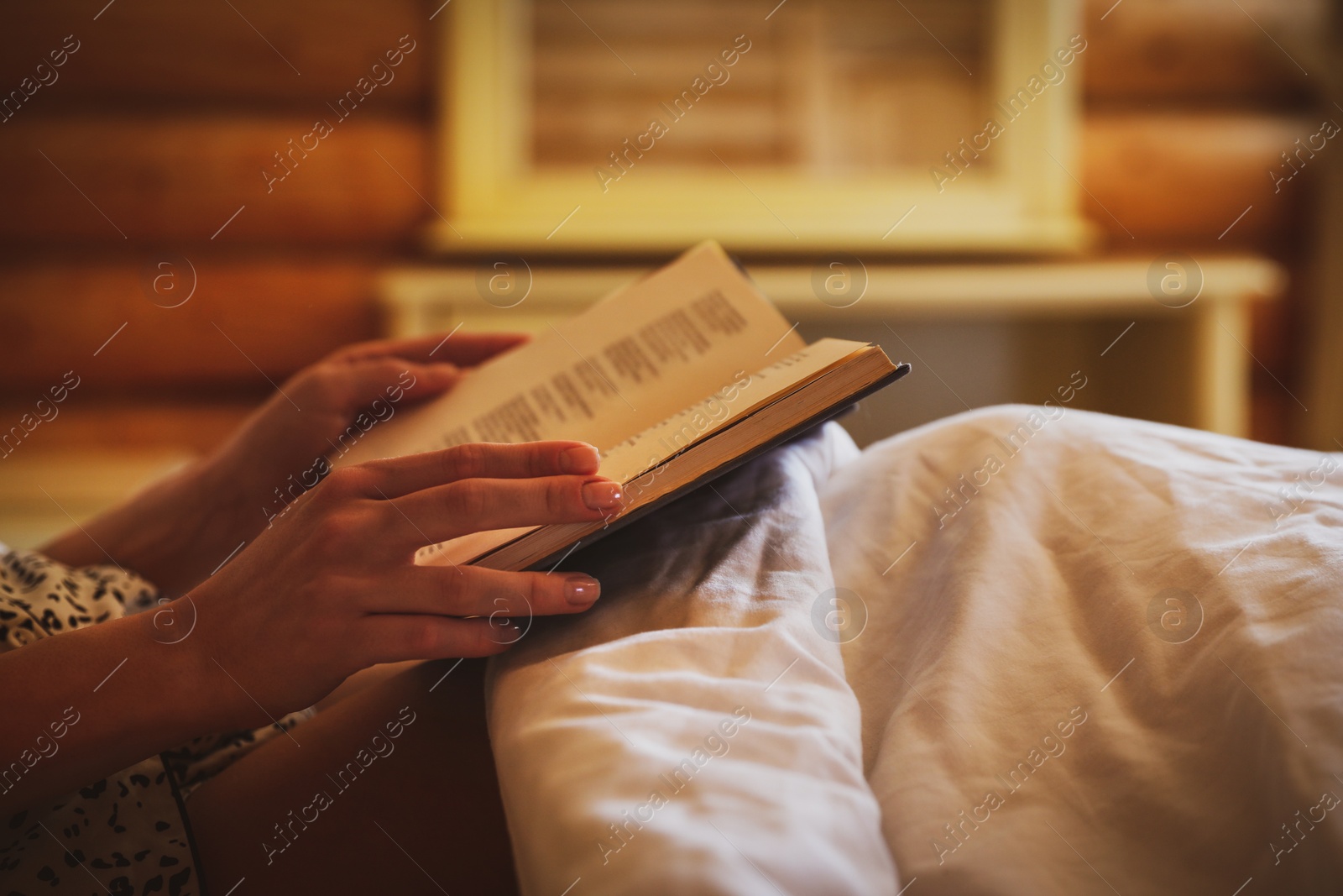 Photo of Woman reading book in bed at home, closeup