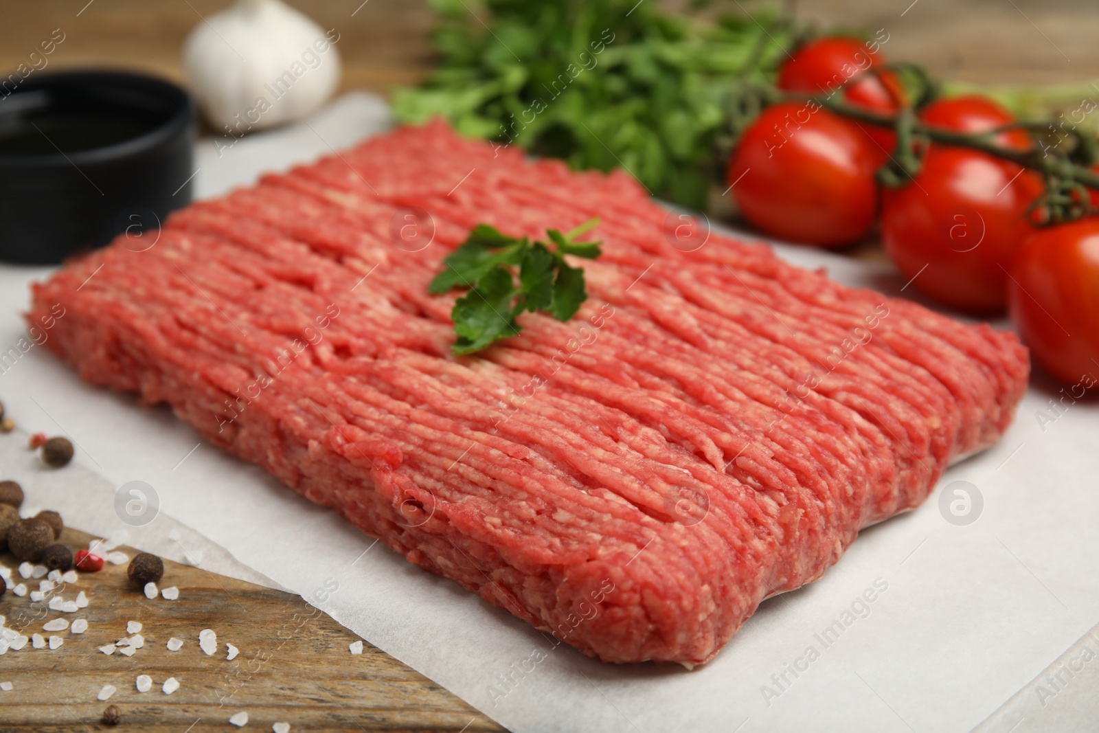 Photo of Raw fresh minced meat, tomatoes and other ingredients on wooden table. Space for text