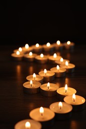 Burning candles on wooden table in darkness