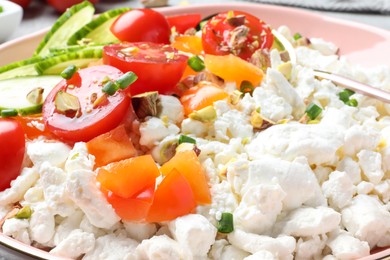 Photo of Delicious cottage cheese with vegetables, pistachios and green onion in bowl, closeup. Tasty breakfast