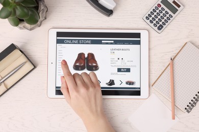 Photo of Woman with tablet shopping online at white wooden table, top view