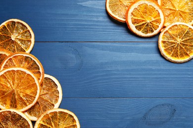 Photo of Dry orange slices on blue wooden table, flat lay. Space for text