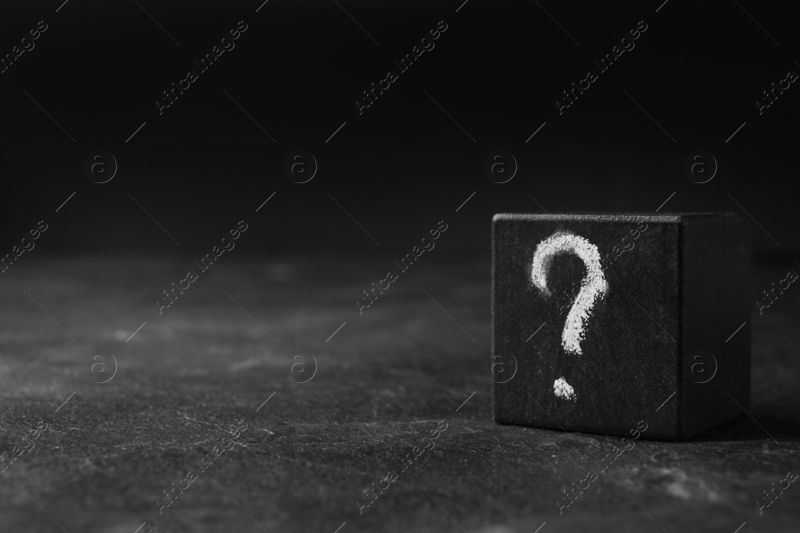 Photo of Wooden cube with question mark on black stone table. Space for text