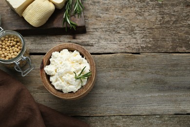 Photo of Delicious tofu cream cheese with rosemary on wooden table, flat lay. Space for text