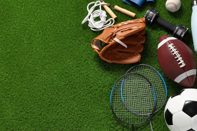 Photo of Different sports equipment on green grass, flat lay. Space for text