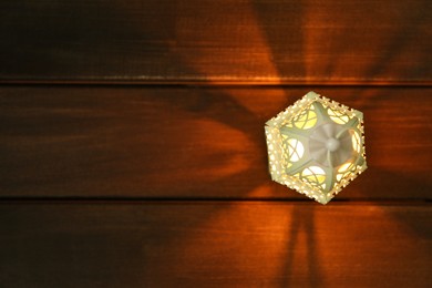 Photo of Decorative Arabic lantern on wooden table, top view. Space for text