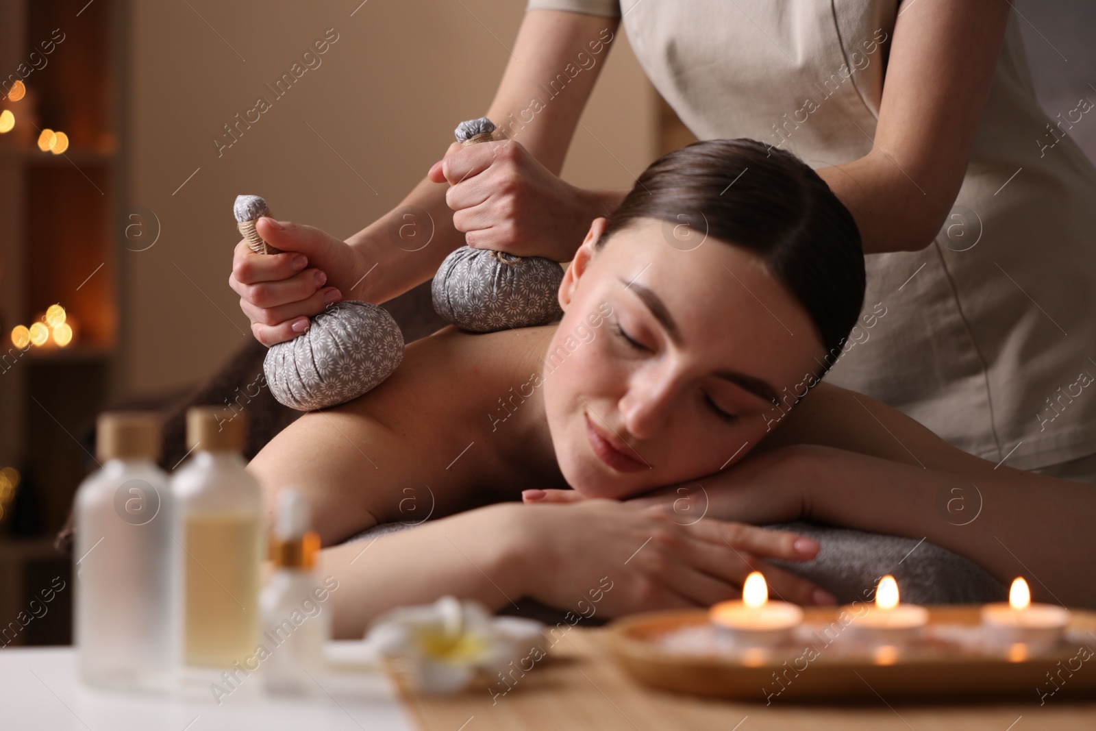 Photo of Spa therapy. Beautiful young woman lying on table during herbal bag massage in salon