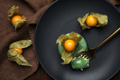 Photo of Delicious mousse cake decorated with physalis fruit on wooden table, flat lay