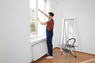 Professional construction worker installing plastic window indoors