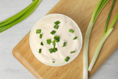 Photo of Fresh sour cream with onion on white wooden table, flat lay