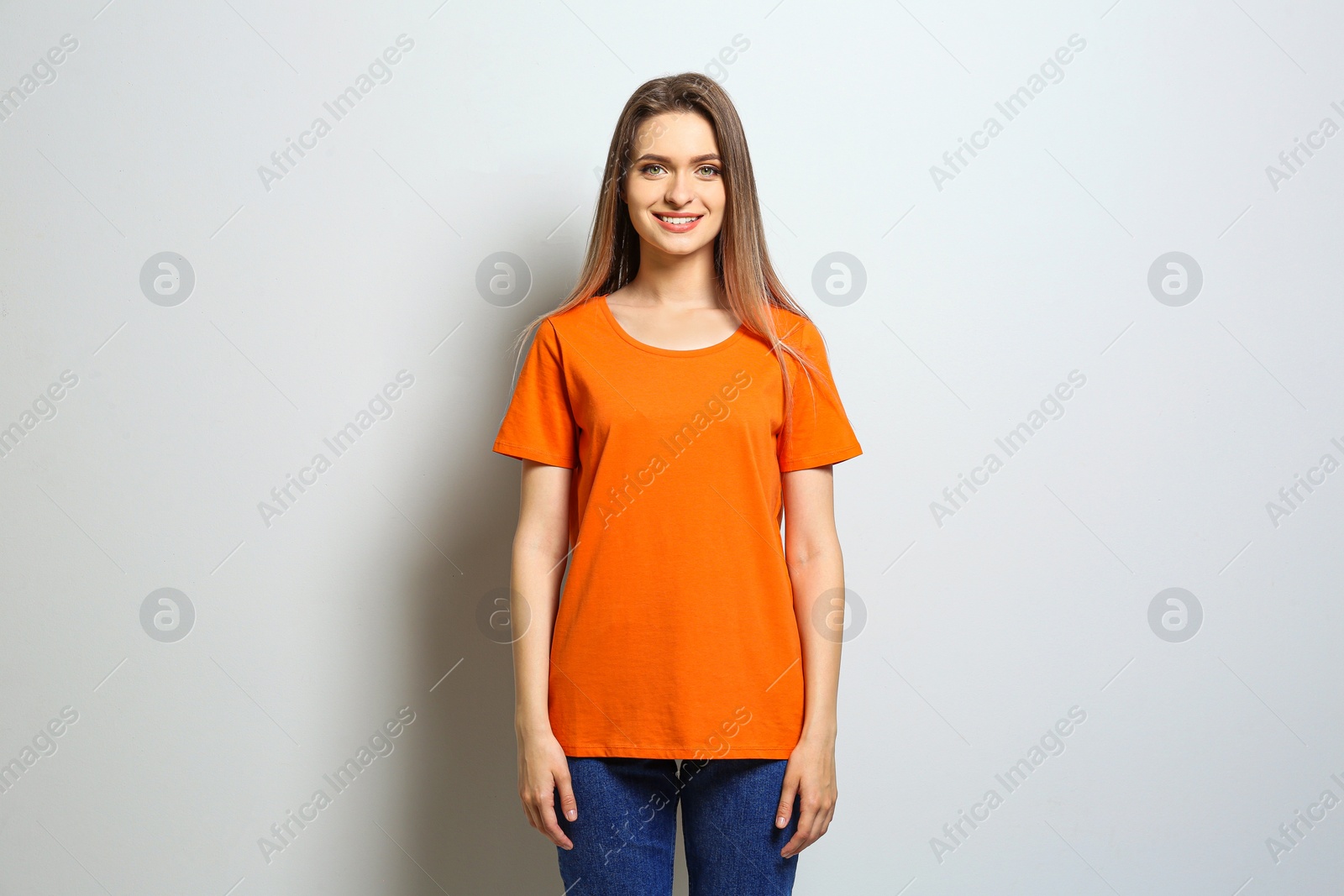 Photo of Young woman wearing blank t-shirt on light background. Mockup for design