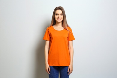 Photo of Young woman wearing blank t-shirt on light background. Mockup for design