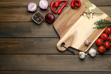 Photo of Cutting board and vegetables on wooden table, flat lay with space for text. Cooking utensil