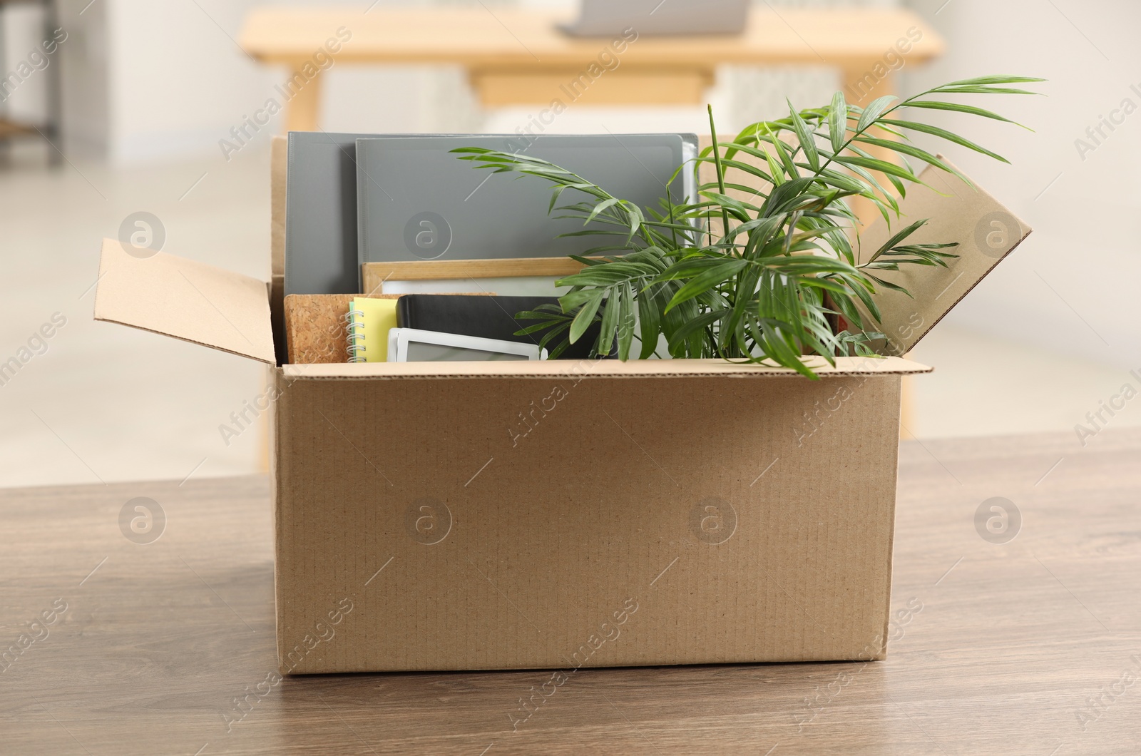 Photo of Unemployment problem. Box with worker's personal belongings on table in office