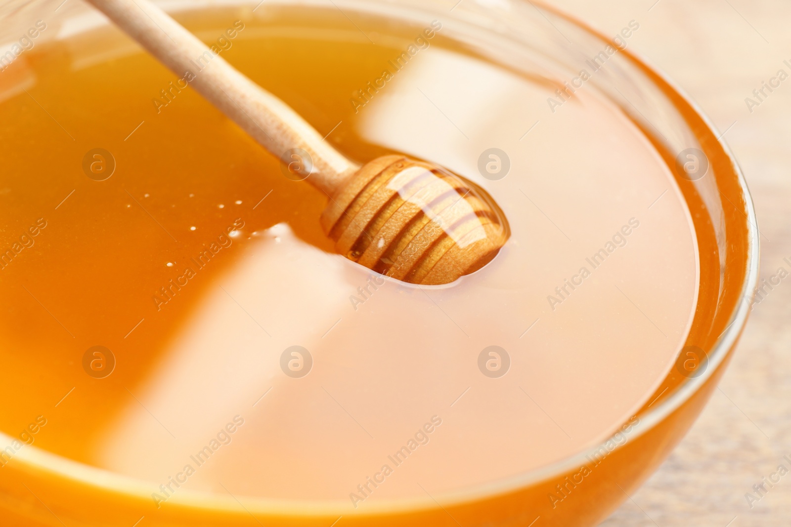 Photo of Tasty honey in glass bowl on table, closeup