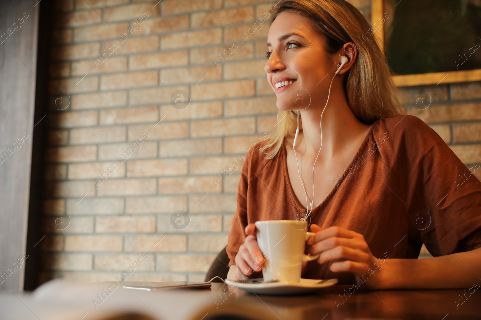 Photo of Woman listening to audiobook at table in cafe